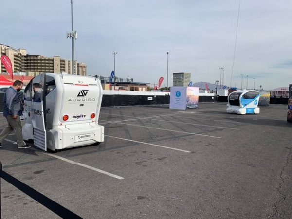 Two self-driving pods take guests for a ride in a car park at a UK show