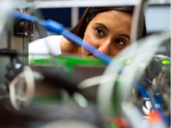 A woman peering through wires and electrical units